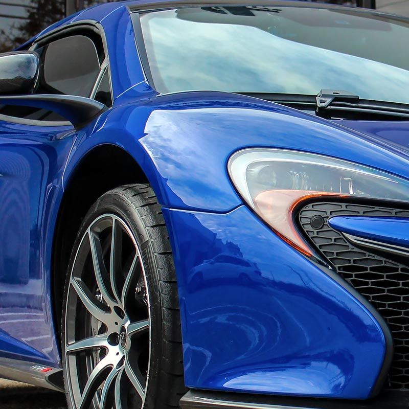 Blue sports car front end with black grille and silver wheel close-up