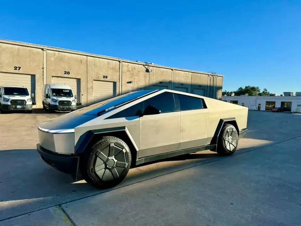 White Tesla Cybertruck parked outdoors on pavement beside a beige warehouse