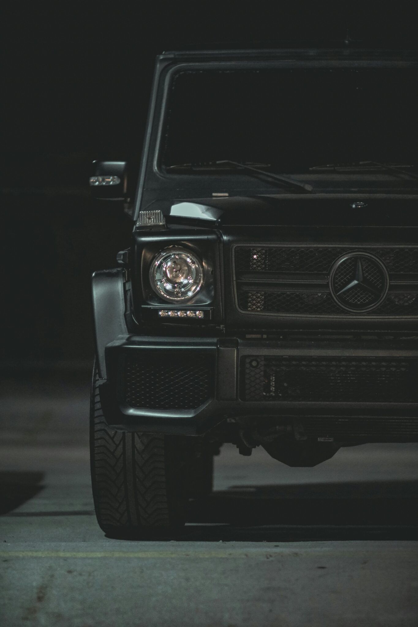 Front view of a black Mercedes-Benz G-Wagon in a dark garage.