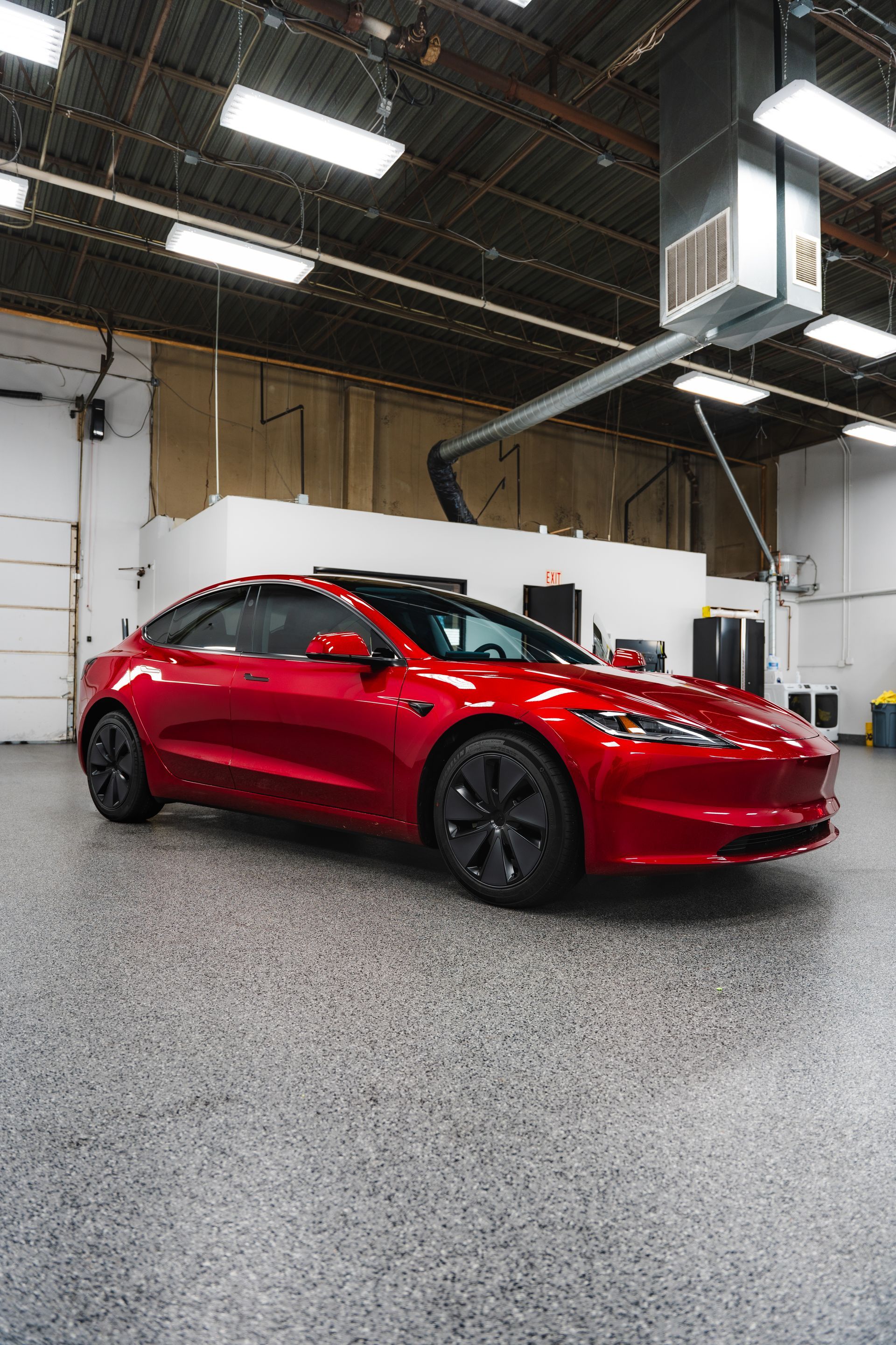 Red sports car in a garage with a polished concrete floor and overhead lights
