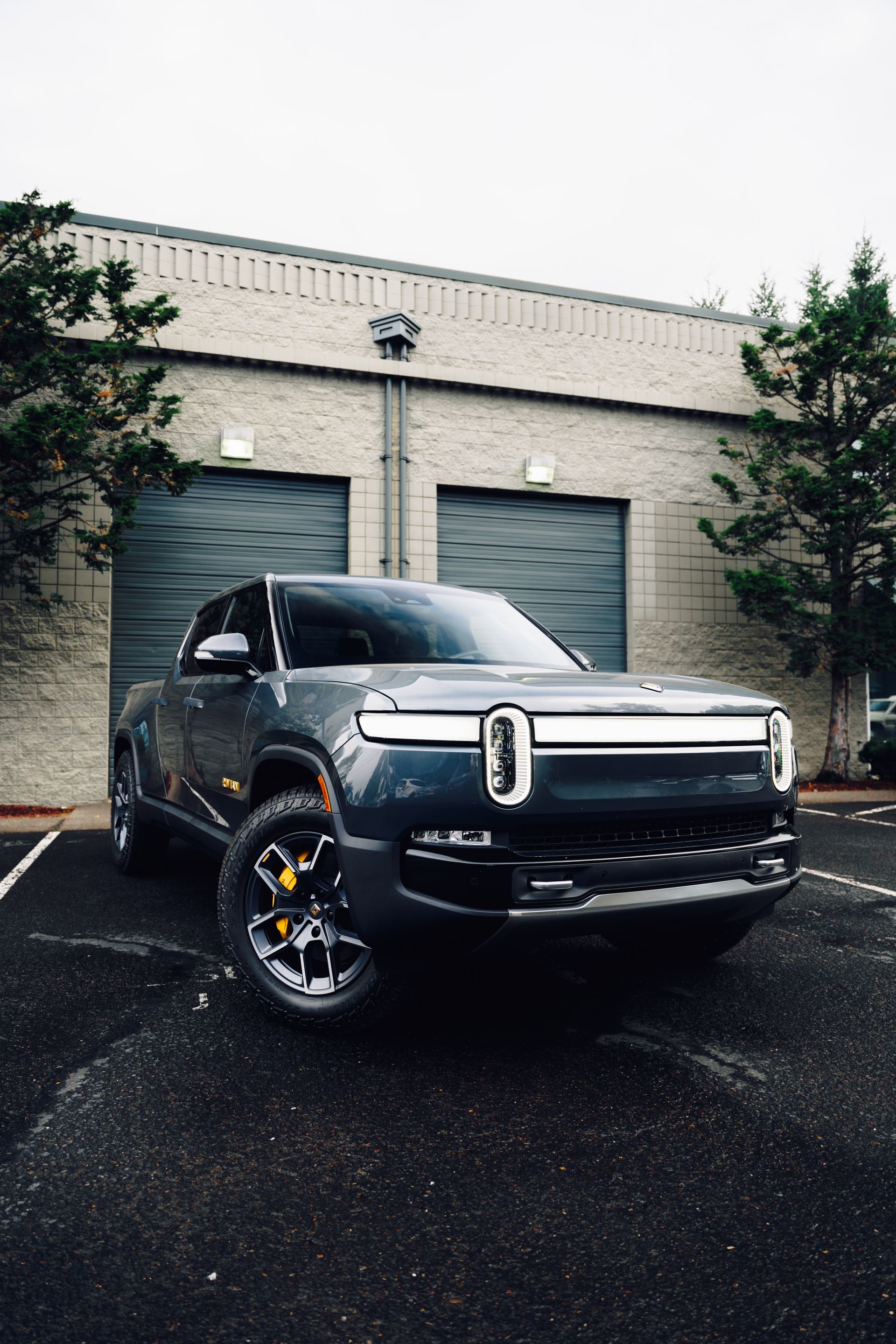 Black pickup truck parked outside a warehouse on a wet lot