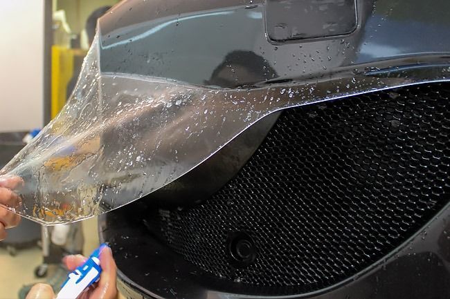 Applying clear protective film to a car’s front grille and bumper