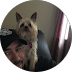 Person holding a small tan dog in front of a mirror in a dim room