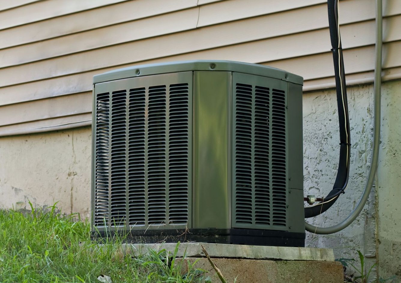 An air conditioner is attached to the side of a house