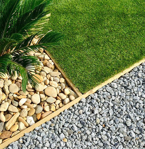 A man is laying a roll of artificial grass on the ground.