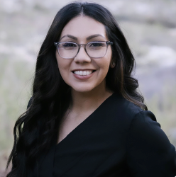 A woman wearing glasses and a black shirt is smiling for the camera.
