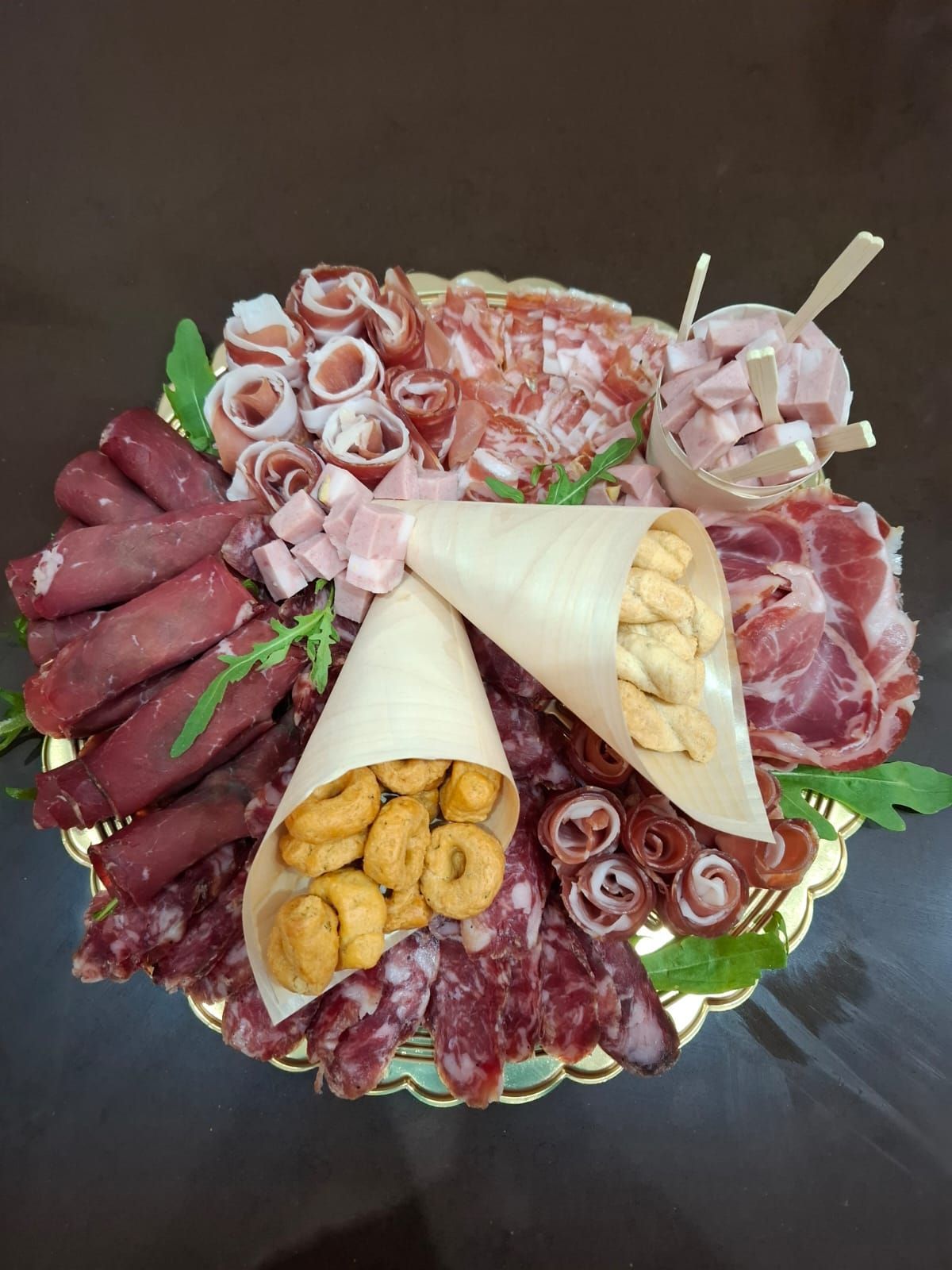 Un assortimento di salumi, formaggi e stuzzichini disposti su un piatto.