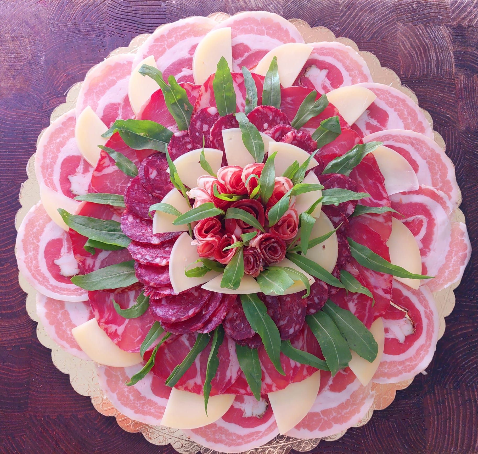 Torta floreale rosa e bianca con petali a strati e foglie verdi su sfondo viola.