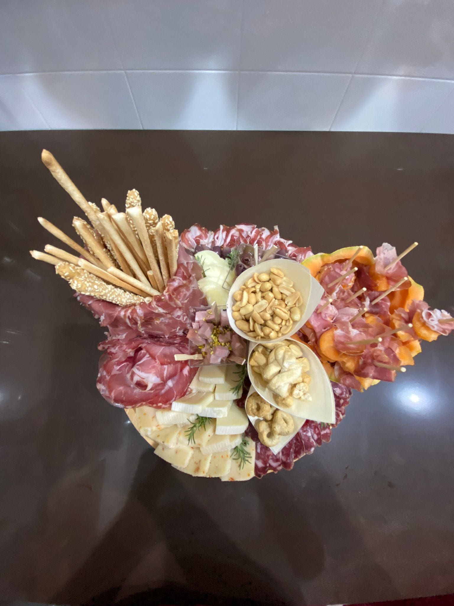 Tagliere di salumi, formaggi, cracker e pretzel su un tavolo scuro