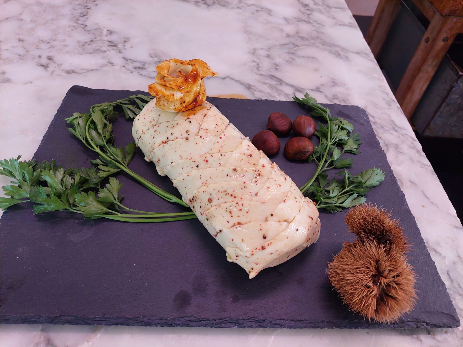 Pasta sfoglia ricoperta di briciole su un tagliere di ardesia con verdure, frutti di bosco e castagne su un tavolo di marmo.
