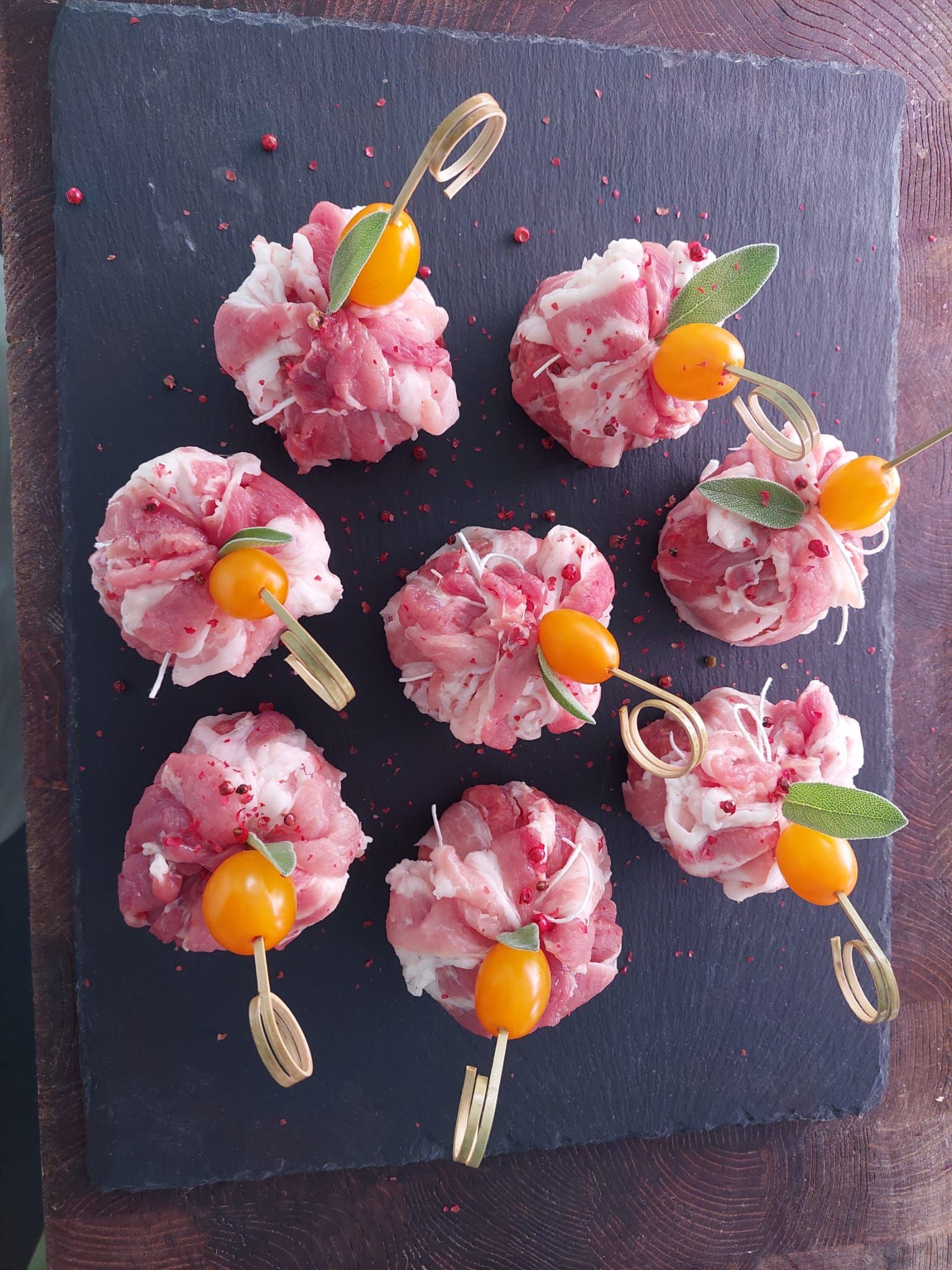 Bocconcini di dessert rosa su un tagliere di ardesia scura, guarniti con fette d'arancia e foglie di menta.