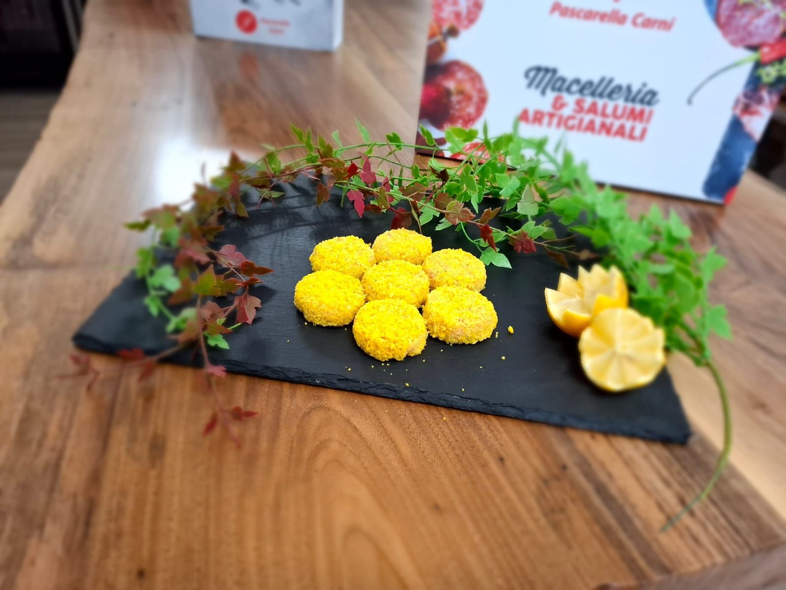 Biscotti gialli su un vassoio di ardesia nera con guarnizione verde su un tavolo di legno.