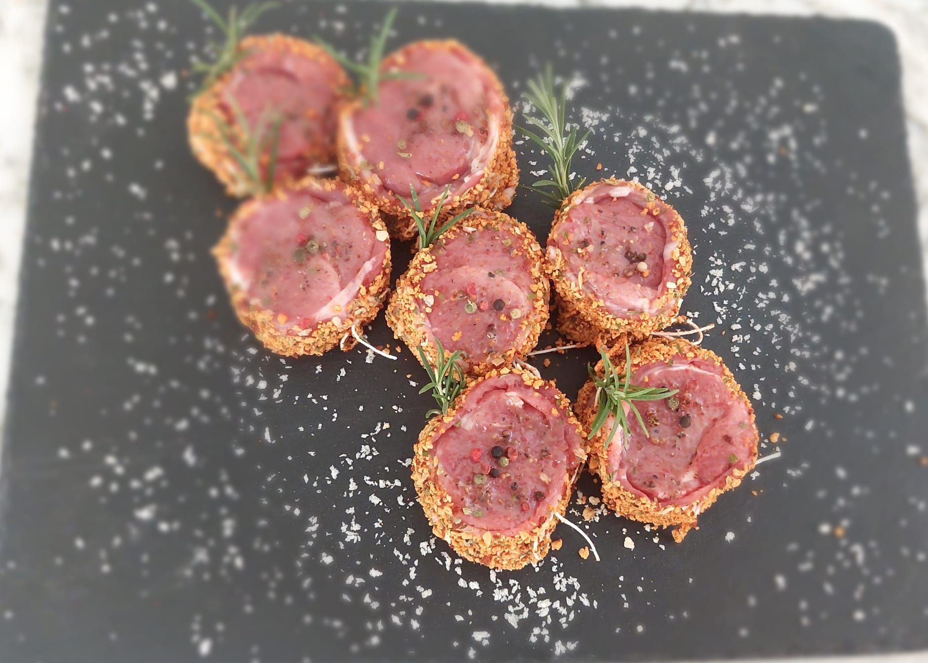 Piatto a base di barbabietole affettate, servito su un piatto nero, cosparso di formaggio grattugiato e guarnito con erbe aromatiche.