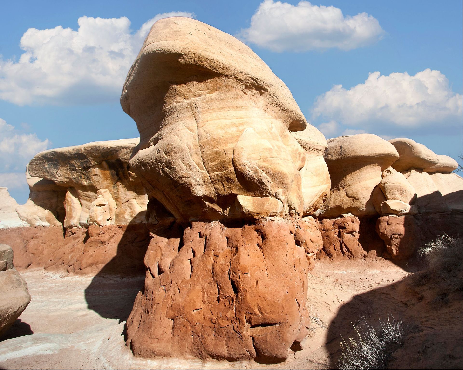 Desert rock formations with large mushroom-shaped boulders under a bright blue sky