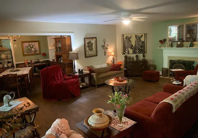 Living room with red couches, floral sofa, antique furniture, and a fireplace.