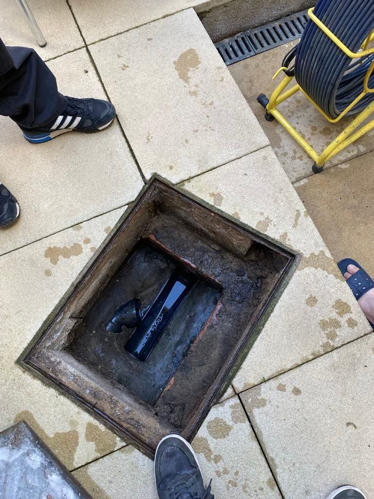 A person is standing next to a manhole cover on a tiled floor in Portskewett