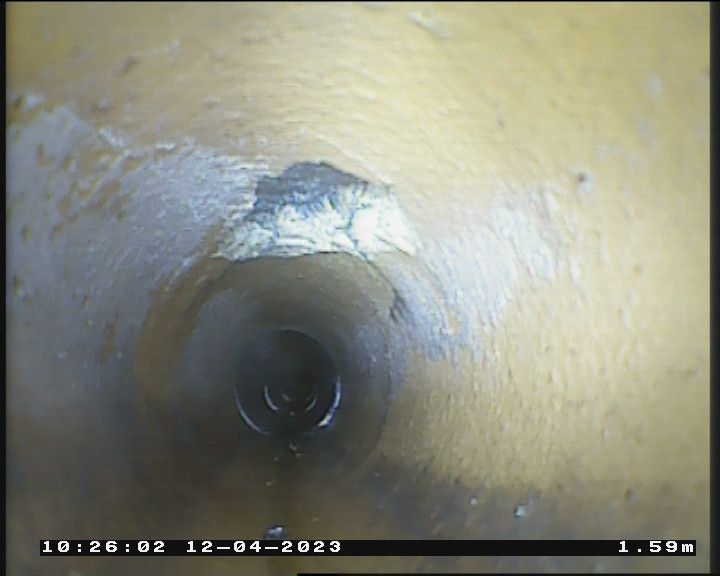 A close up of a hole in a pipe with the date 12-04-2023