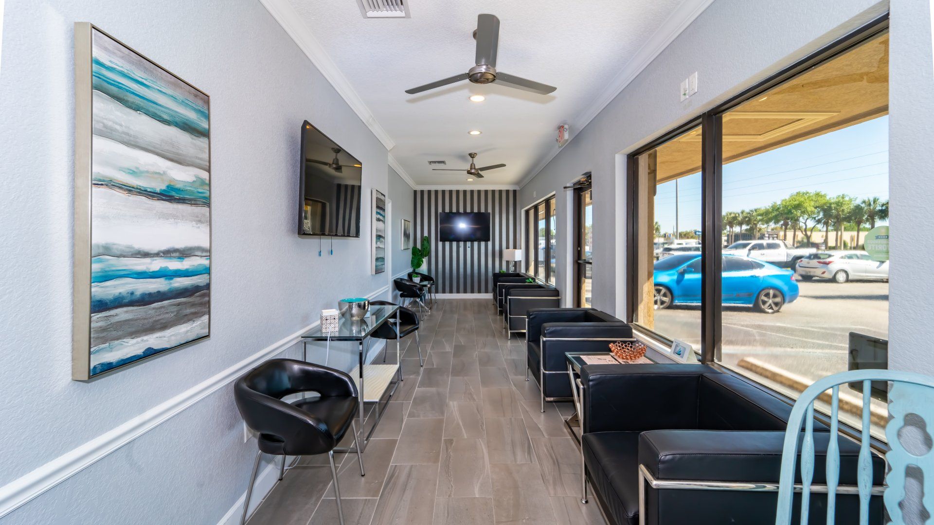 A long waiting room with a lot of chairs and a television on the wall.