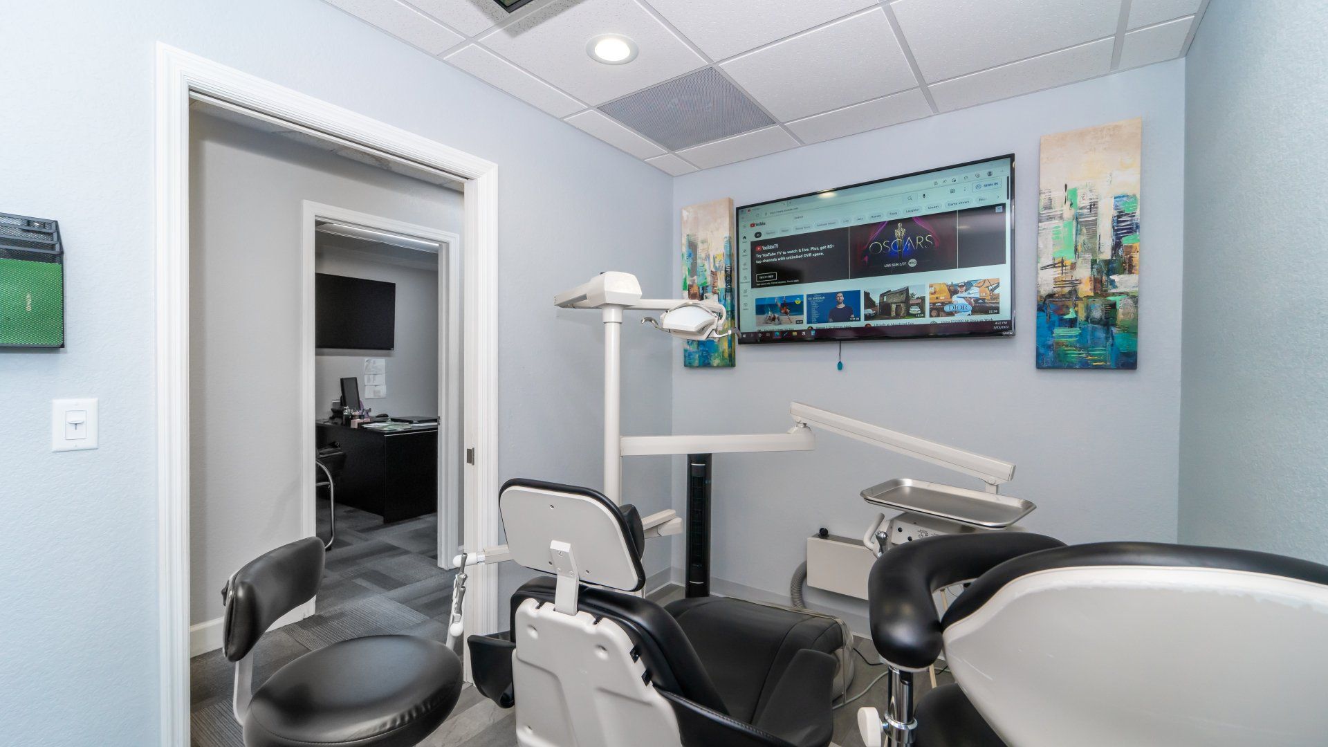 A dental office with a dental chair and a television on the wall.