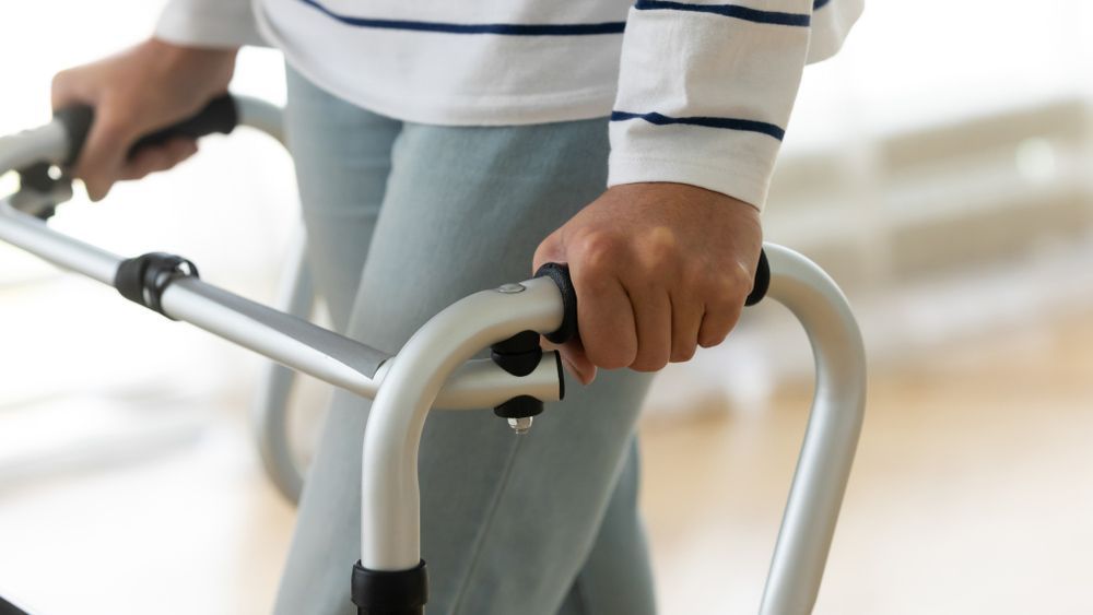A Person Is Using A Walker To Walk On A Wooden Floor — NQ Health In Bayview Heights, QLD