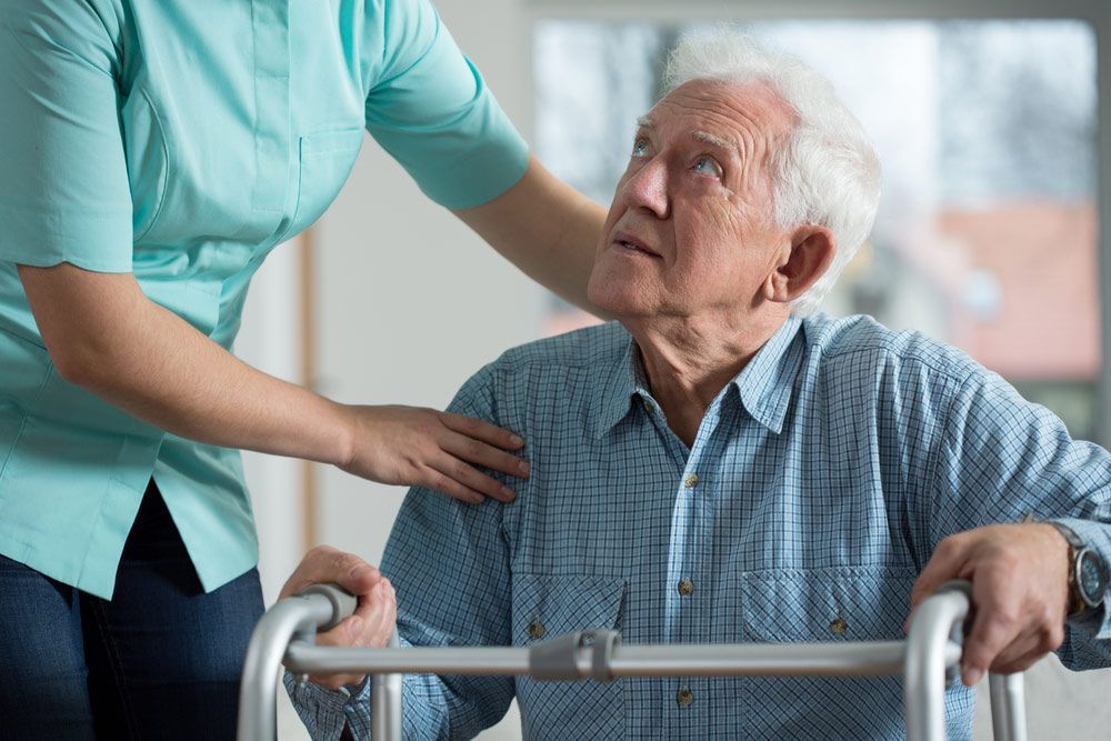 A Woman Is Helping An Elderly Man Use A Walker — NQ Health In Bayview Heights, QLD