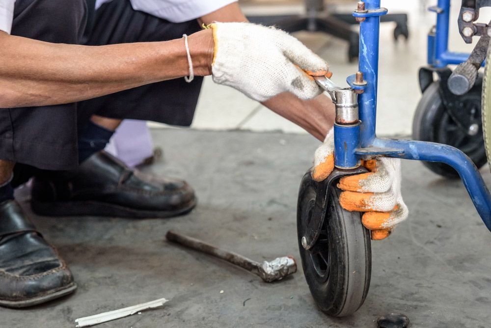 A Man Is Fixing A Wheelchair With A Wrench — NQ Health In Bayview Heights, QLD