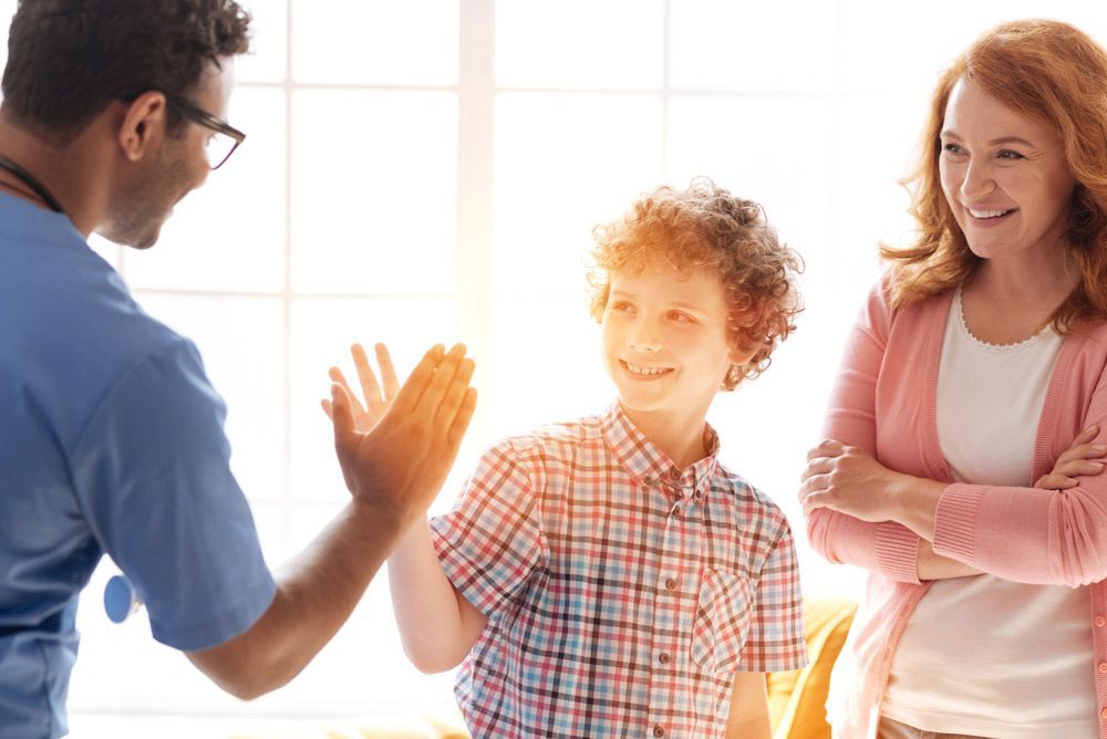 A Doctor Is Giving A High Five To A Boy And A Woman — NQ Health In Bayview Heights, QLD
