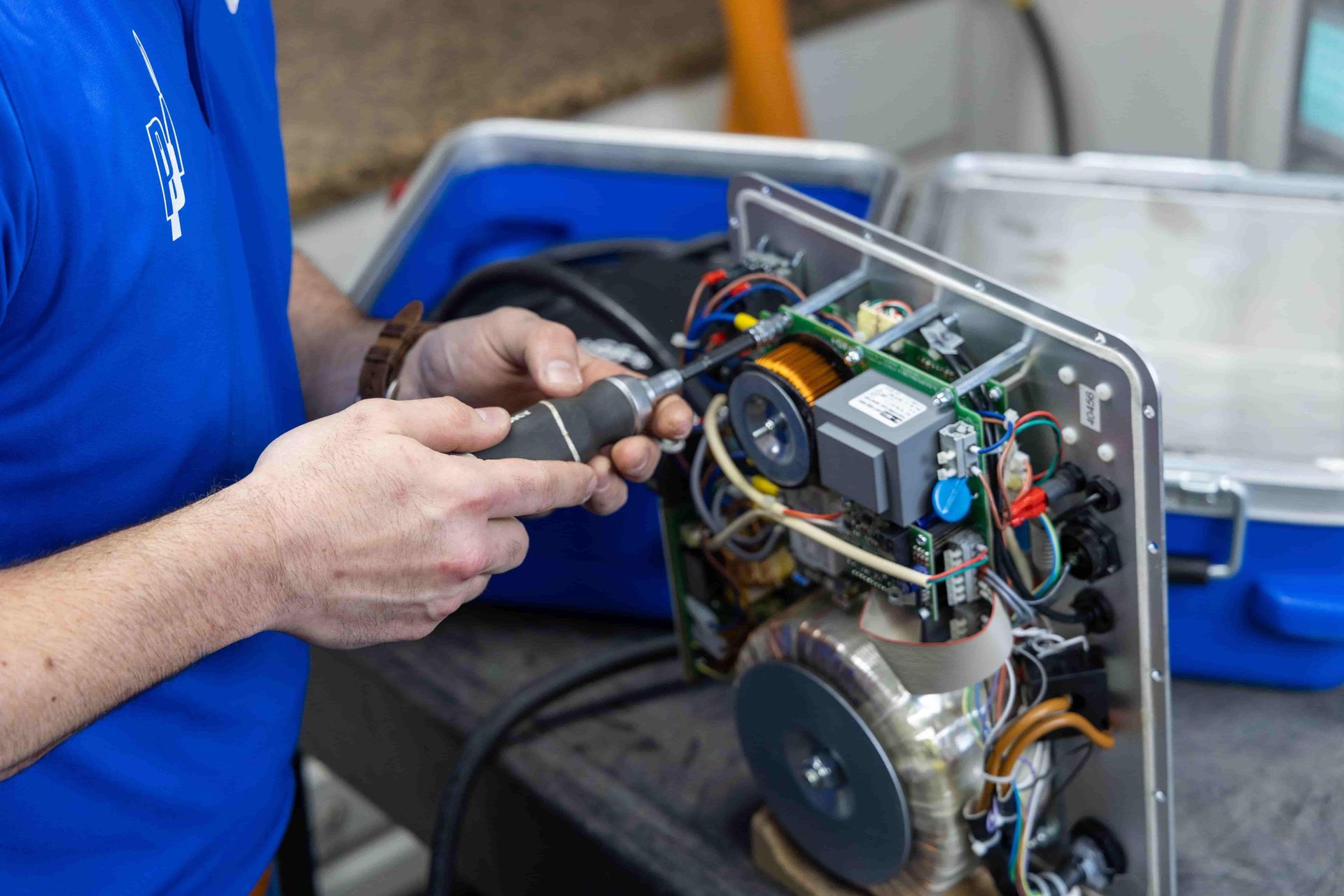 A man in a blue shirt is working on a machine.