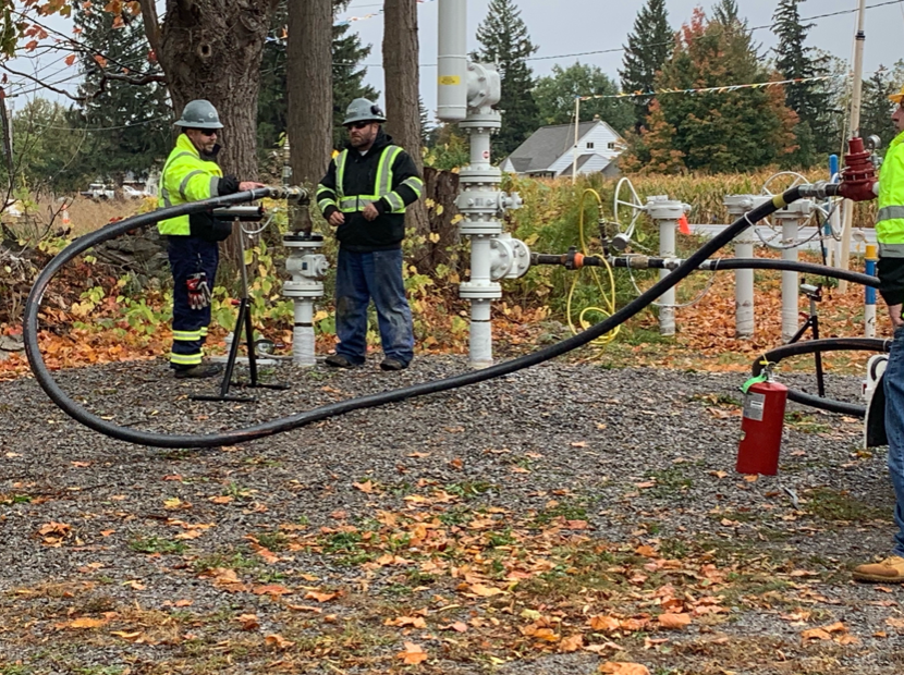 A group of men are working on a large hose in a field.