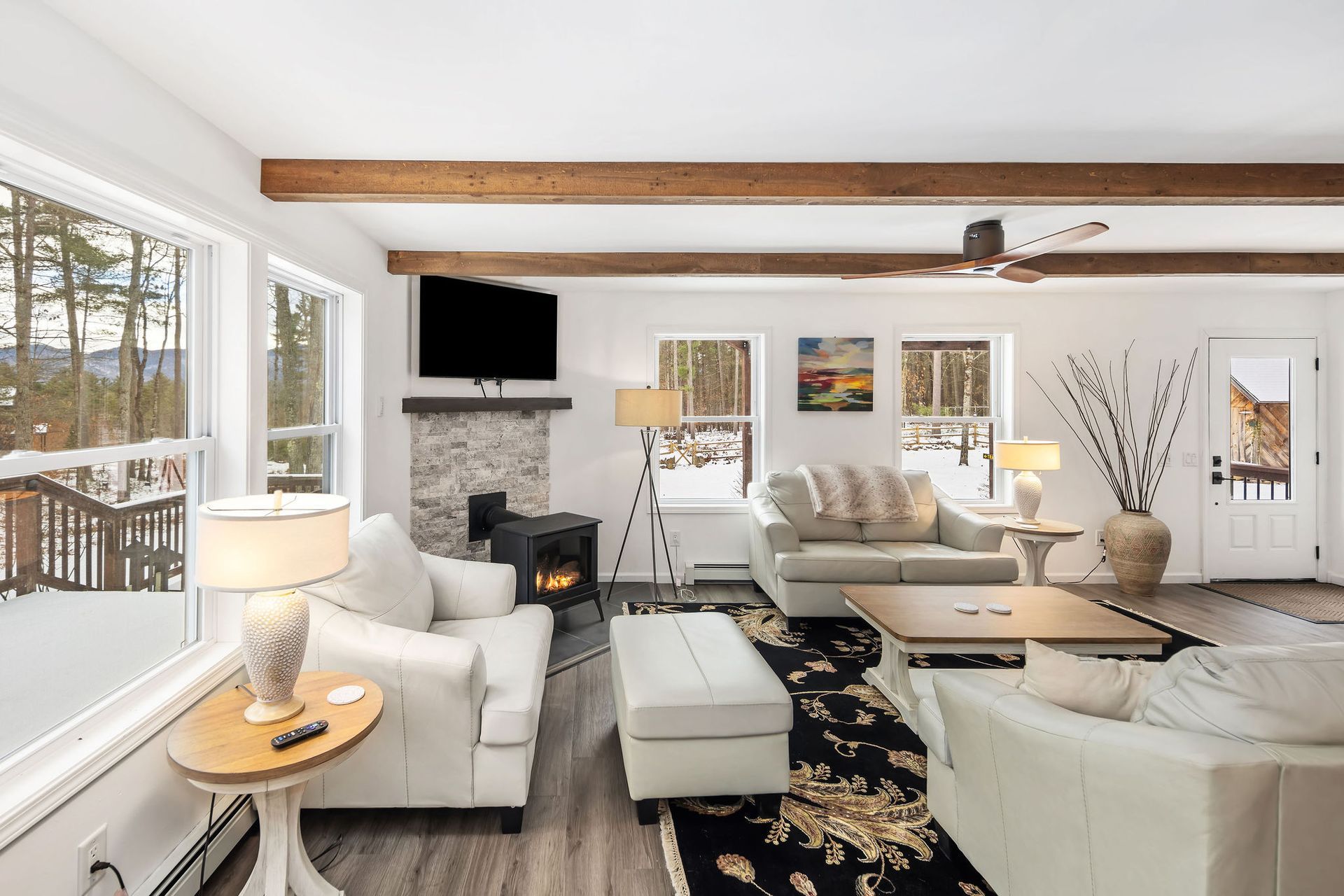 The living room at Adirondack View Lodge located near Whiteface Mountain. Modern Decor, Large TV, Gas Stove, and views of the mountains and woods.