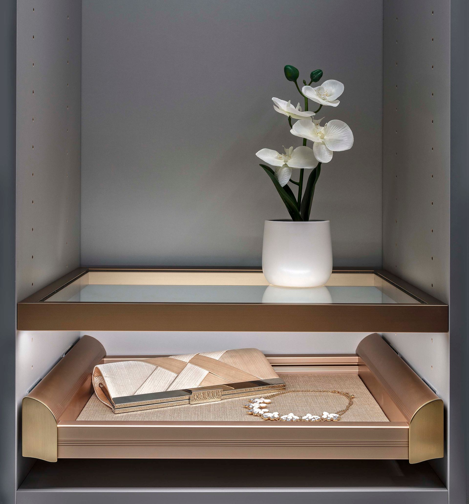 Shelf with white flower arrangement and decorative items, lit from above and below.