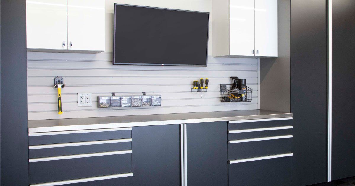 a black and white garage storage system with a flat screen tv on the wall .