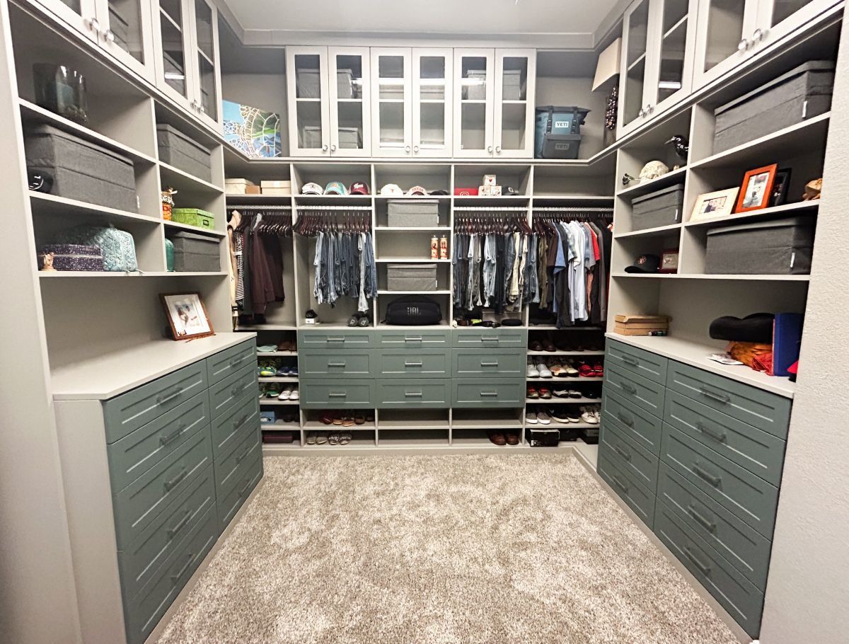 A walk in closet with lots of shelves and drawers filled with clothes and shoes.