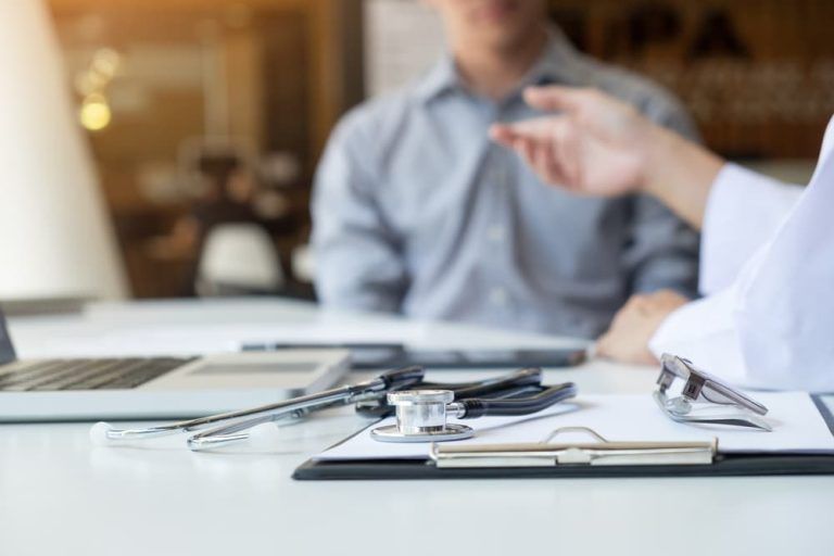 A doctor is talking to a patient while sitting at a desk.