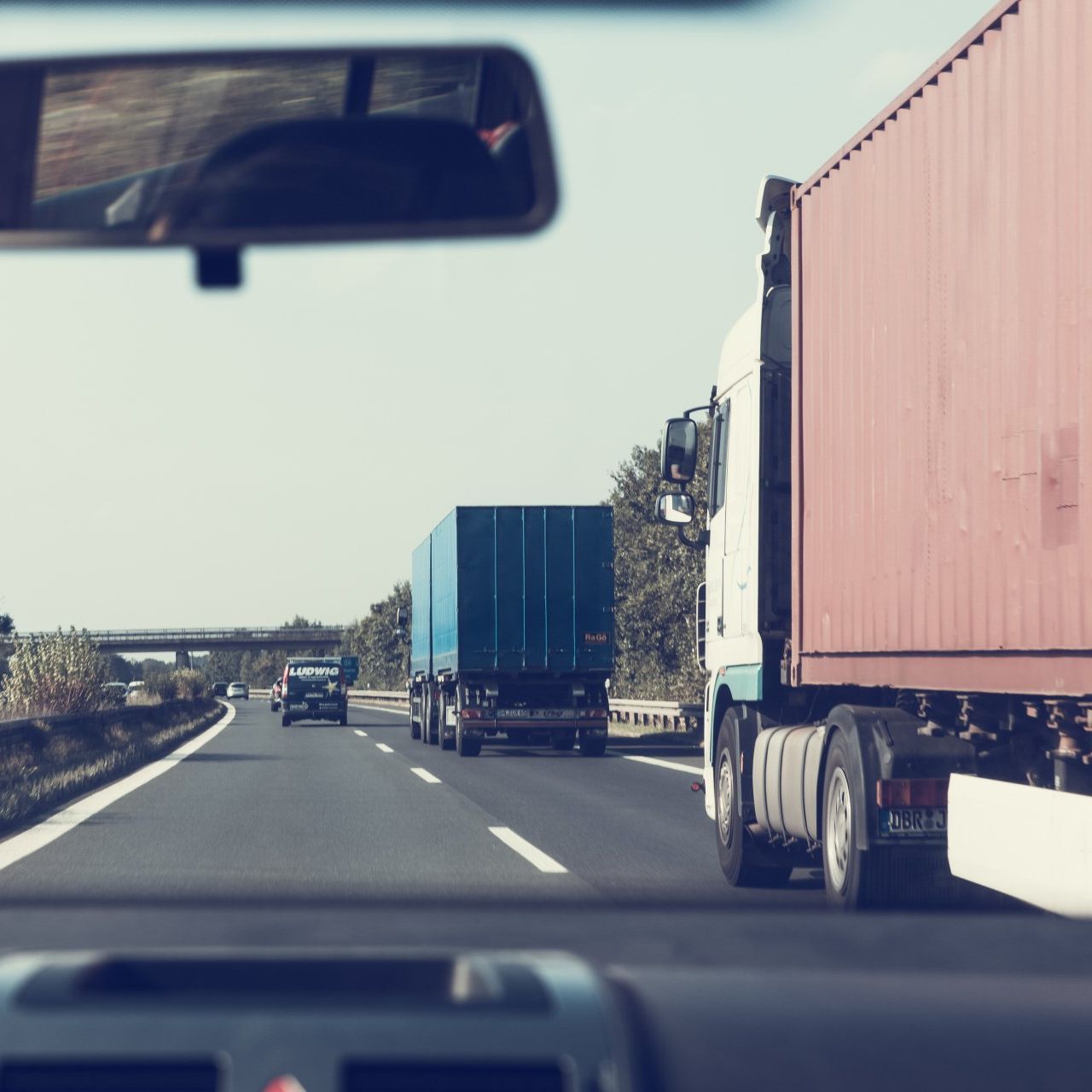 A truck is driving down a highway next to another truck.