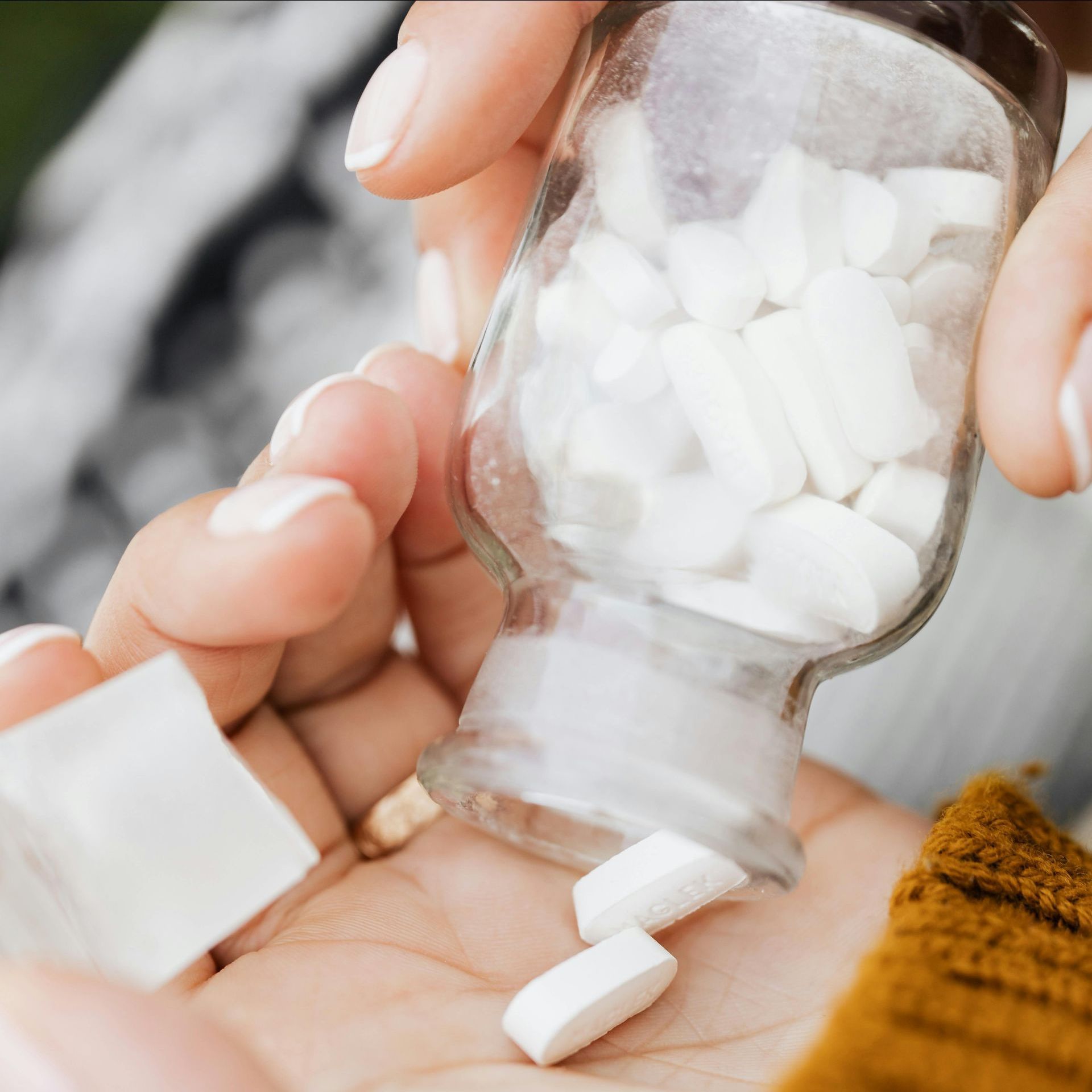 A person is pouring white pills into their hand