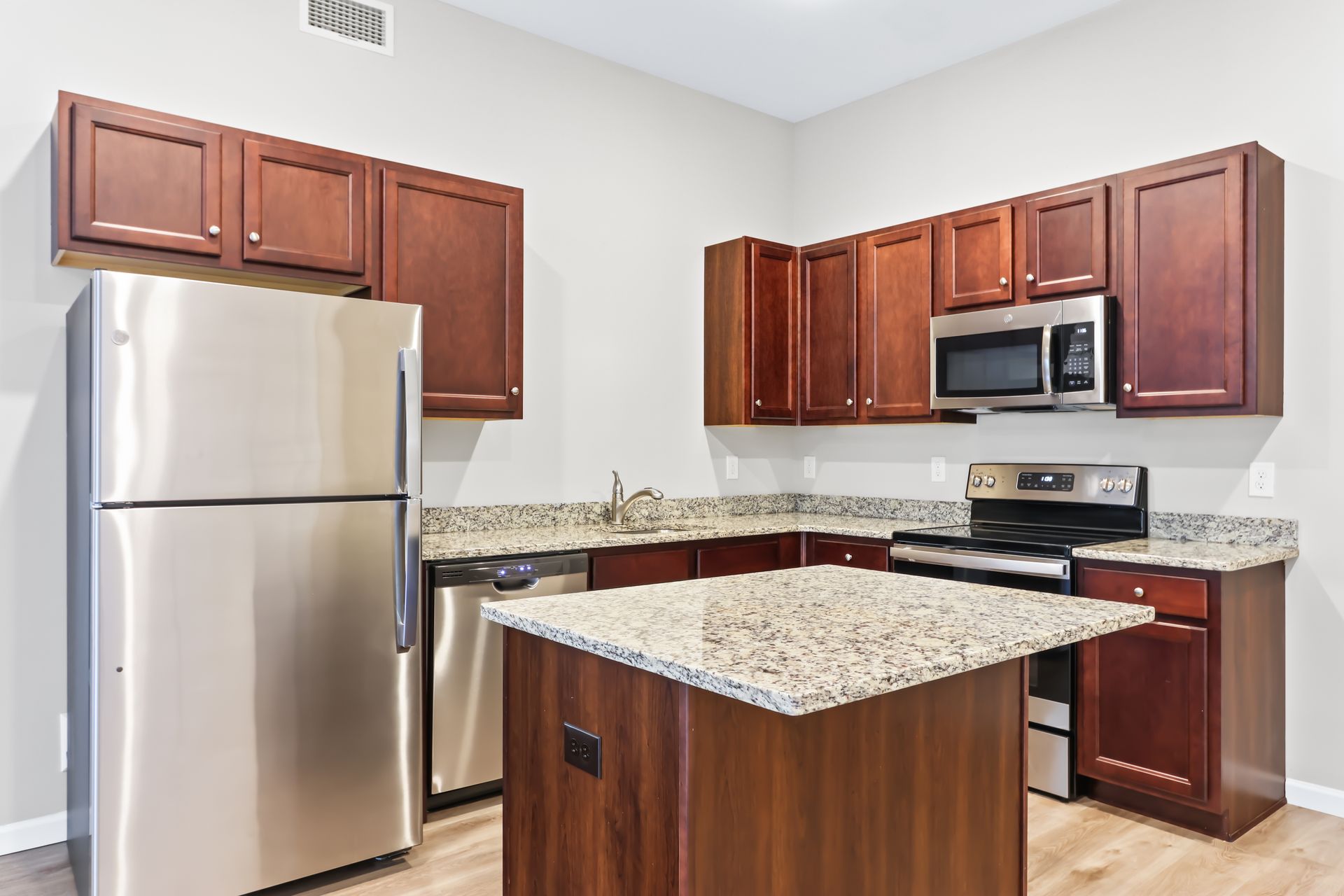 Kitchen with stainless steel appliances, dark wood cabinets, granite countertops, and an island.
