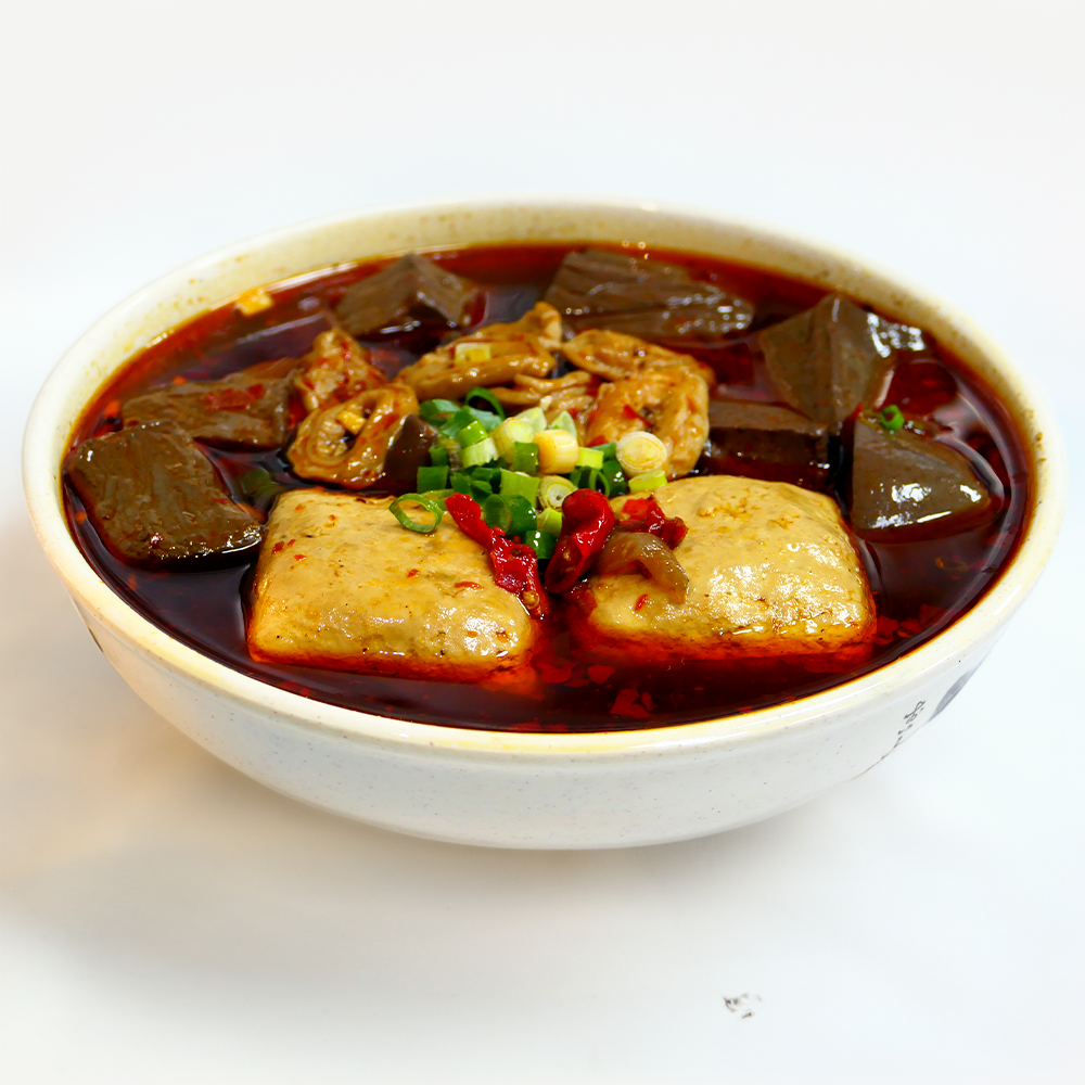 一碗台灣美食，以豆腐、豬血和內臟為特色，浸在紅色的湯汁中，並撒上蔥花。
