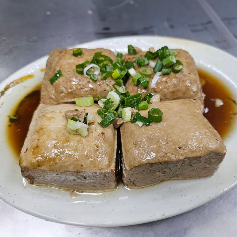 一碗紅燒豆腐，配上湯汁和切碎的蔥花。