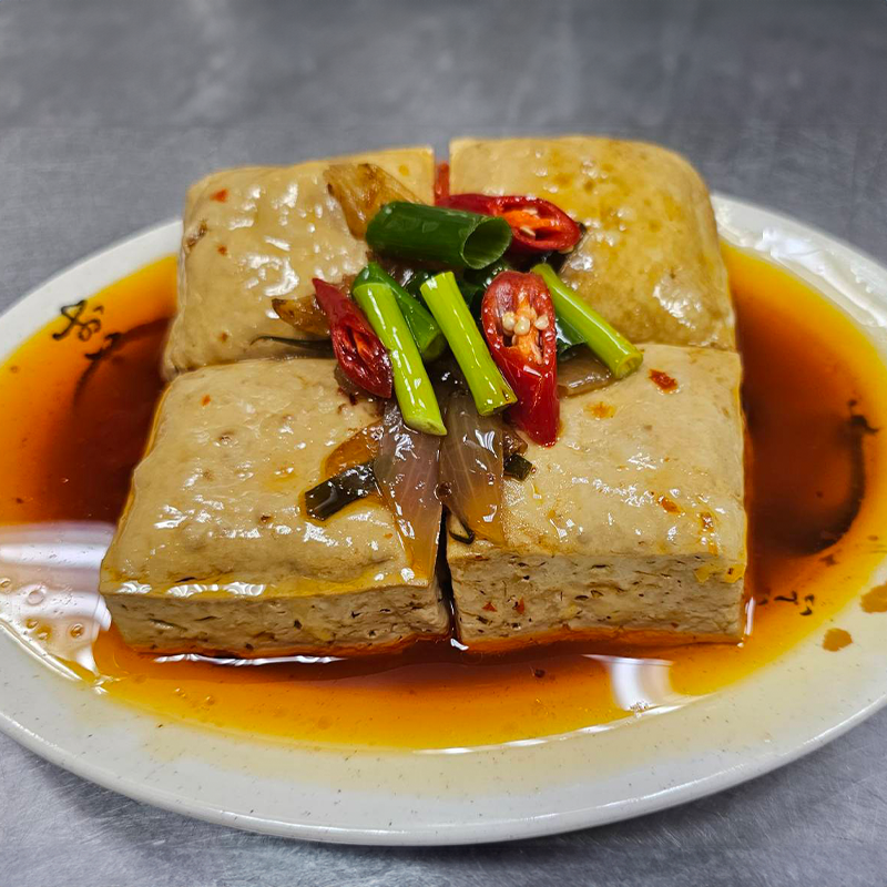 一碗方豆腐，淋上紅辣椒油，撒上洋蔥和辣椒片。