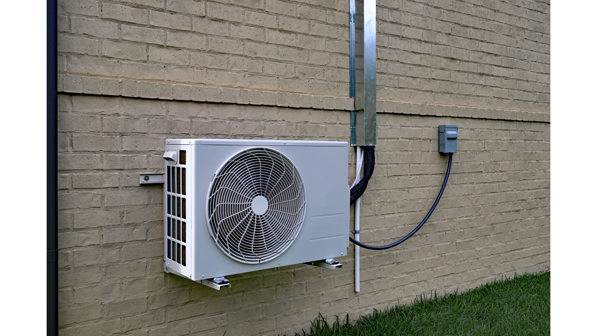 A white air conditioner is mounted on the side of a brick building.
