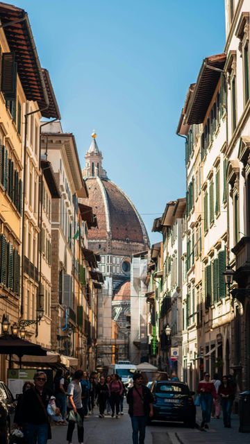 Stretta via storica pedonale che conduce alla cupola del Duomo di Firenze sotto un cielo azzurro.