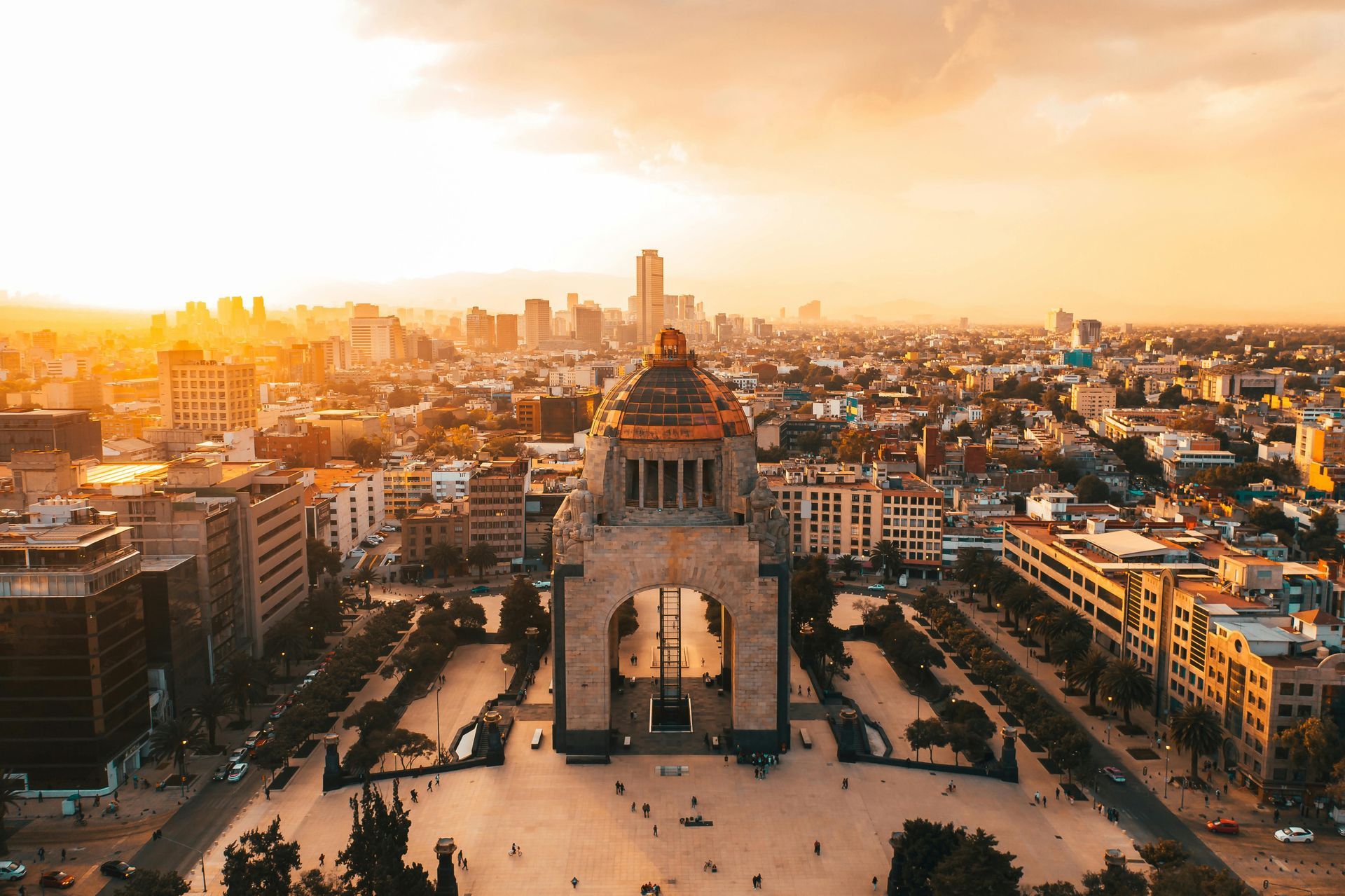 Veduta aerea del tramonto dello skyline di una città con un grande monumento in pietra al centro di una piazza.