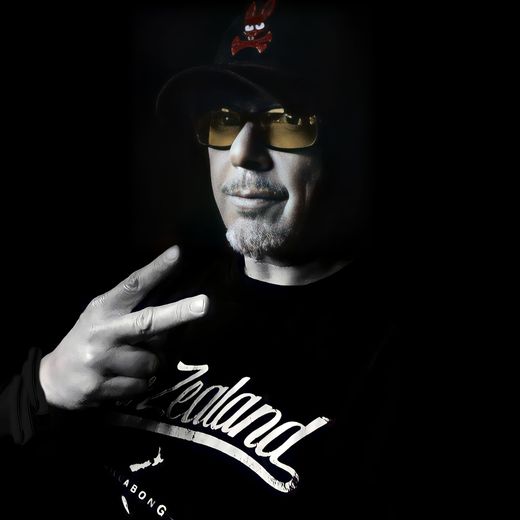 A man wearing a hat and sunglasses is wearing a zealand shirt