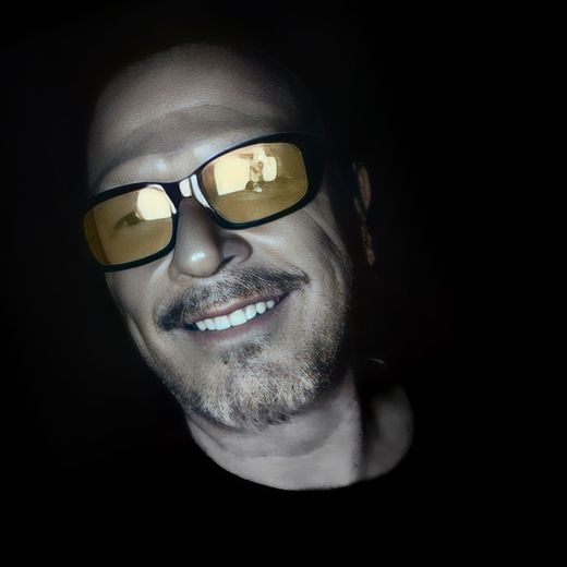 A man wearing sunglasses is smiling in the dark
