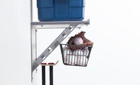 a basket filled with baseballs is hanging from a shelf .