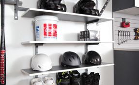 garage shelving filled with shelves filled with baseball equipment and helmets .