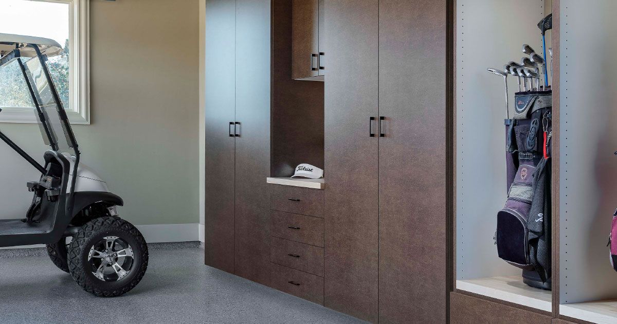 a car is parked in a garage with lots of cabinets .