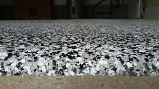 a close up of a black and white epoxy floor coating with a staircase in the background .