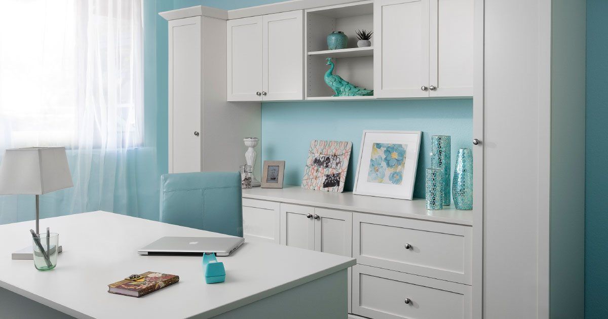 A white desk with a laptop on it in a room with blue walls.